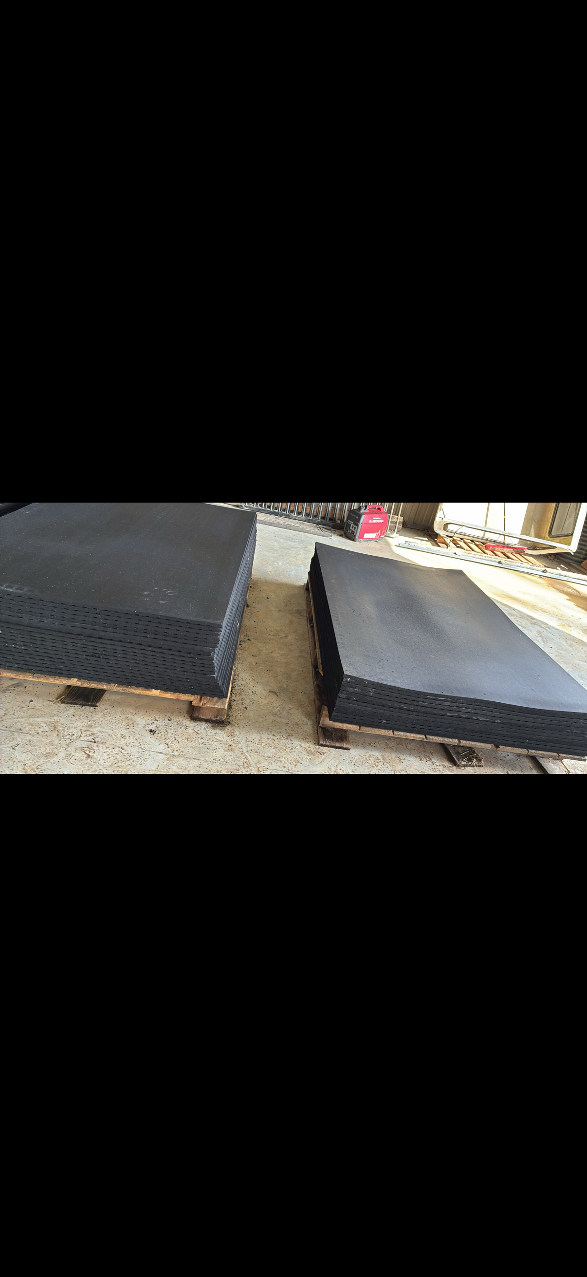 Two pallets of stacked rubber mats in warehouse